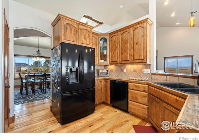 kitchen featuring black appliances, tasteful backsplash, a sink, and light wood-style floors