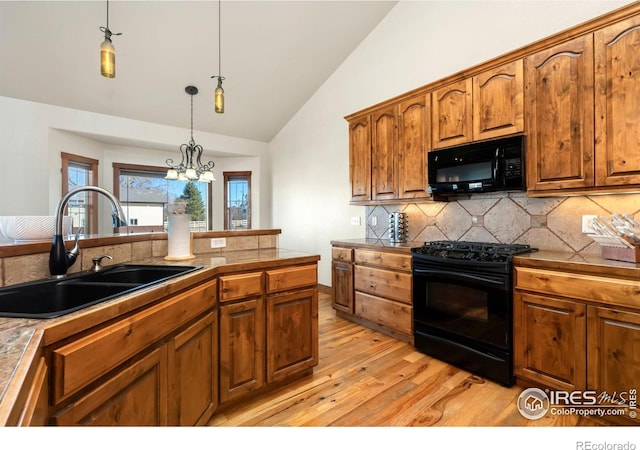 kitchen with brown cabinets, lofted ceiling, hanging light fixtures, a sink, and black appliances