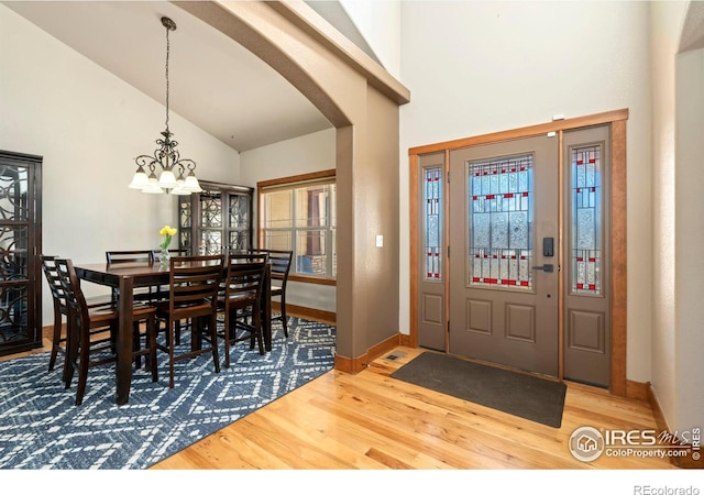 entrance foyer featuring arched walkways, a notable chandelier, baseboards, and wood finished floors