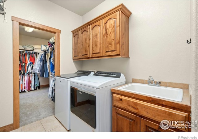 clothes washing area featuring light tile patterned floors, washing machine and dryer, light colored carpet, a sink, and cabinet space