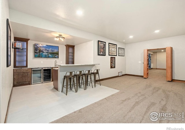 interior space featuring wine cooler, light colored carpet, a sink, visible vents, and indoor wet bar