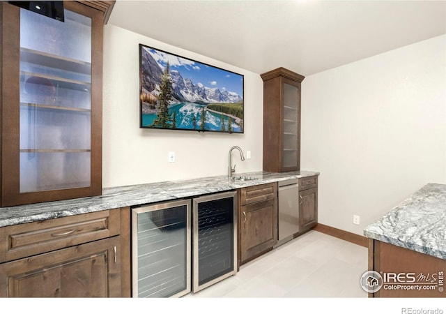 bar with beverage cooler, baseboards, a sink, and dishwasher