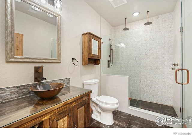 full bathroom with toilet, vanity, a shower stall, and visible vents