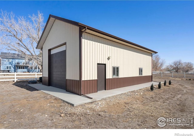 view of side of property with an outbuilding, fence, and a detached garage