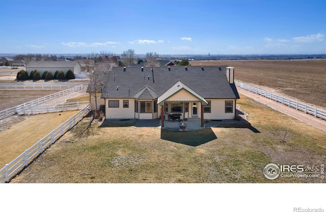 view of front facade featuring a rural view, a patio, and fence