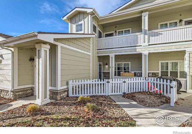 view of front of home with a balcony, a fenced front yard, a gate, and a porch