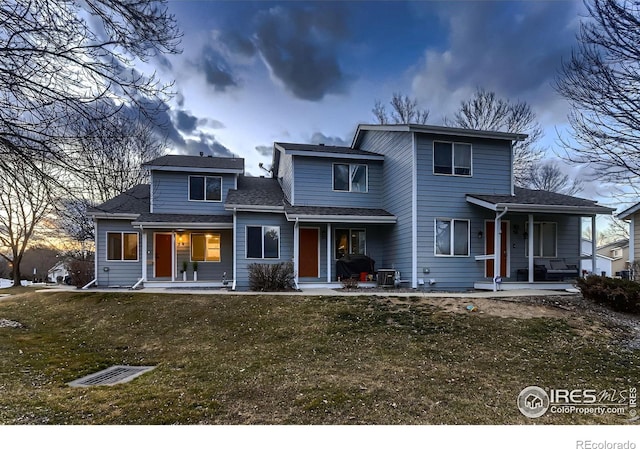 back of property featuring covered porch and a lawn