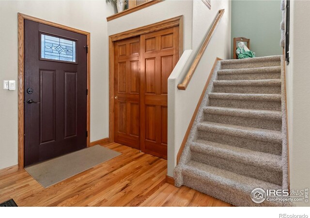 foyer entrance featuring wood finished floors, baseboards, and stairs