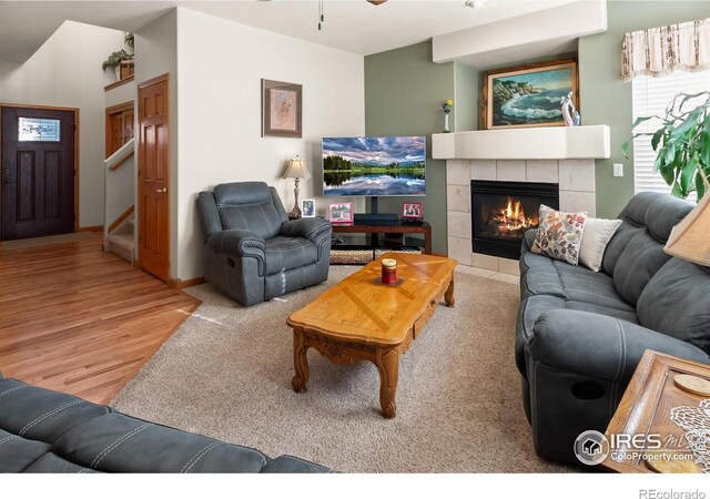 living area featuring a ceiling fan, a fireplace, stairway, and wood finished floors