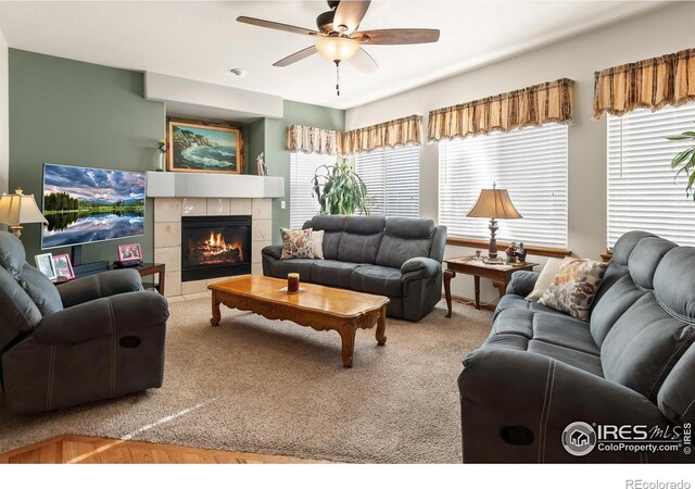 living area with ceiling fan, carpet floors, and a tile fireplace