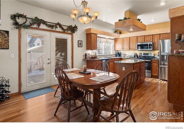 dining space with light wood finished floors, french doors, a chandelier, and baseboards