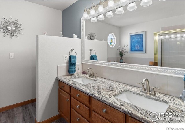 full bath with wood finished floors, a sink, backsplash, and double vanity