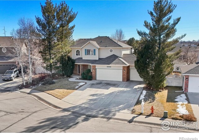 traditional-style home with driveway, an attached garage, fence, and brick siding