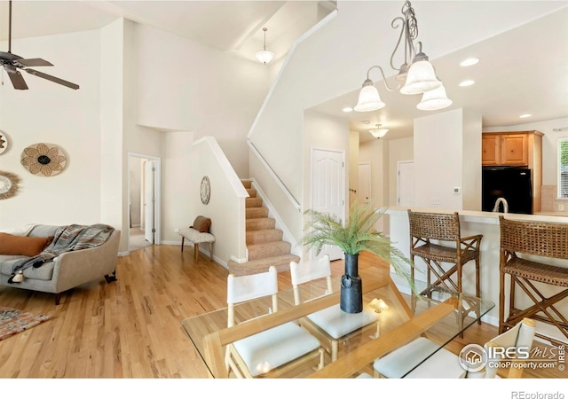 dining space featuring a high ceiling, stairway, light wood-style flooring, and recessed lighting