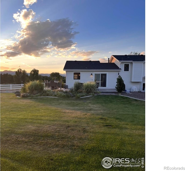 back of property at dusk featuring a yard