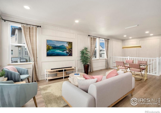 living room with ornamental molding, wood finished floors, and a decorative wall