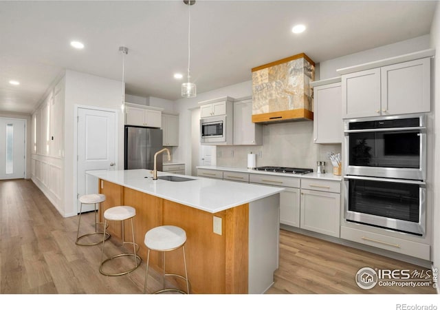 kitchen with tasteful backsplash, a breakfast bar area, appliances with stainless steel finishes, light countertops, and a sink