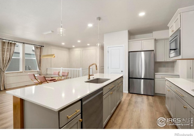 kitchen featuring light wood-style flooring, gray cabinets, stainless steel appliances, light countertops, and a sink