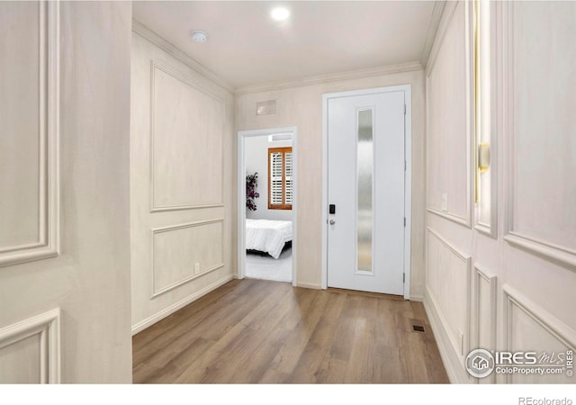 interior space featuring wood finished floors, visible vents, and crown molding