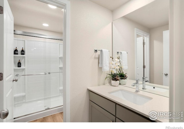 full bath with a stall shower, vanity, and wood finished floors