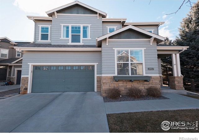 craftsman-style home featuring driveway, stone siding, board and batten siding, and an attached garage