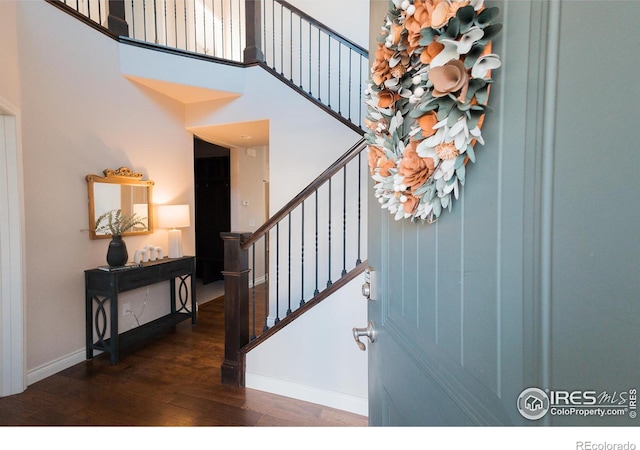 stairs with a high ceiling, wood finished floors, and baseboards