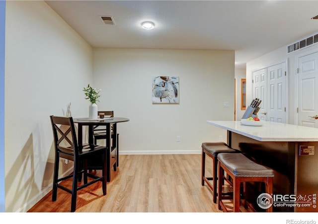 dining area with baseboards, visible vents, and light wood-style floors