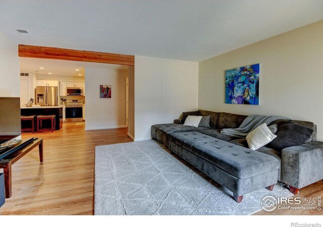 living area with light wood-type flooring, visible vents, and baseboards