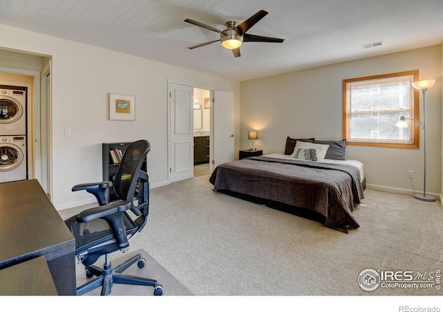 carpeted bedroom featuring stacked washer and dryer, ensuite bath, visible vents, and baseboards