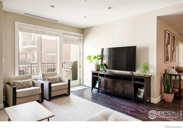 living area featuring visible vents, baseboards, and wood finished floors