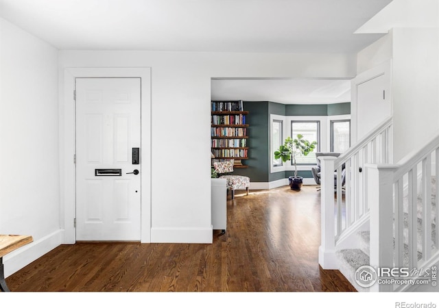 entryway with stairs, baseboards, and wood finished floors