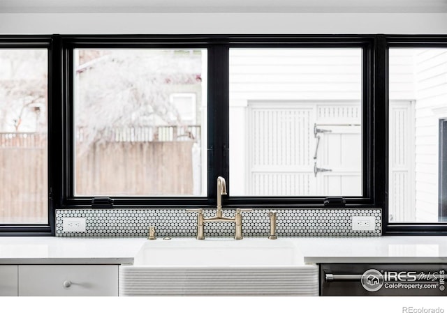 details featuring white cabinets, light countertops, a sink, and dishwashing machine