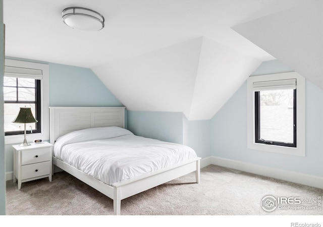 carpeted bedroom with lofted ceiling and baseboards