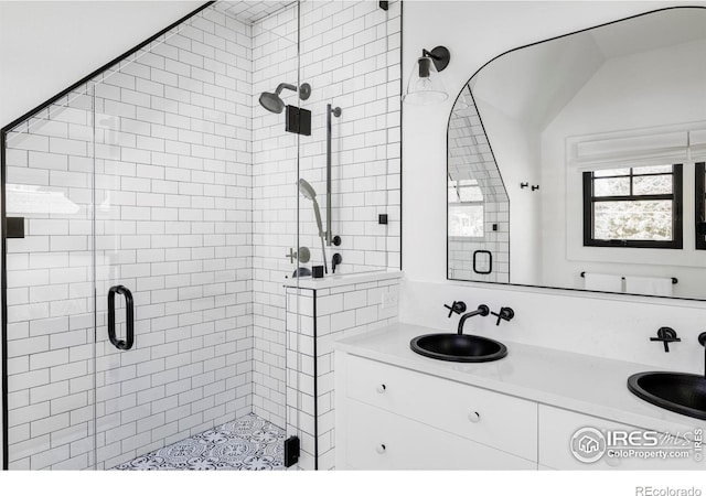 bathroom featuring lofted ceiling, double vanity, a sink, and a shower stall