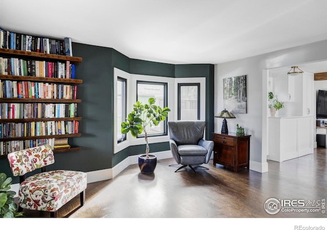 living area with baseboards and wood finished floors