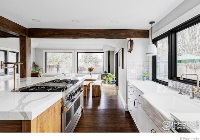 kitchen featuring tasteful backsplash, beamed ceiling, a sink, and double oven range