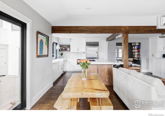 dining room with dark wood-style floors, lofted ceiling, and baseboards