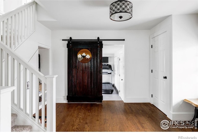 entrance foyer with stairs, wood finished floors, baseboards, and a barn door