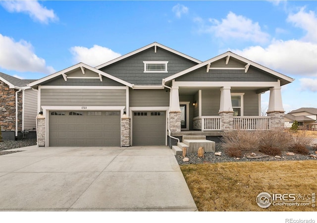 craftsman-style house with driveway, stone siding, an attached garage, and a porch