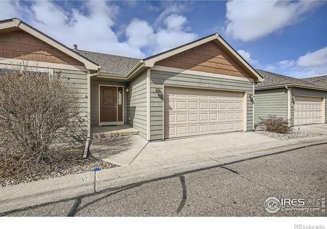 single story home featuring an attached garage, concrete driveway, and roof with shingles