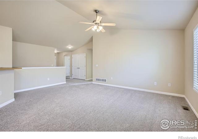 unfurnished room with lofted ceiling, carpet, visible vents, and baseboards