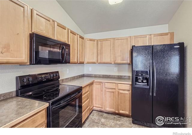 kitchen featuring black appliances, light brown cabinets, light countertops, and vaulted ceiling