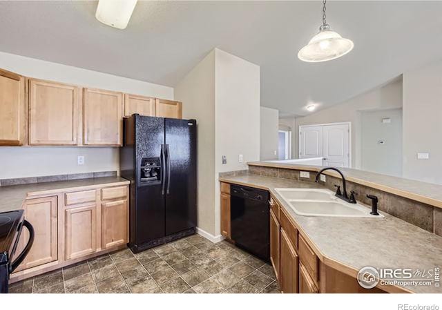 kitchen featuring light brown cabinetry, light countertops, hanging light fixtures, black appliances, and a sink