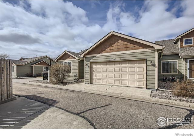 view of front of property with an attached garage, driveway, and fence