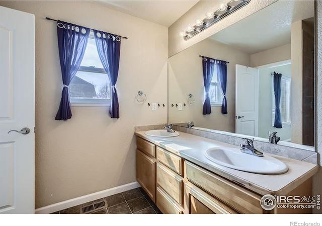 bathroom featuring double vanity, tile patterned floors, baseboards, and a sink