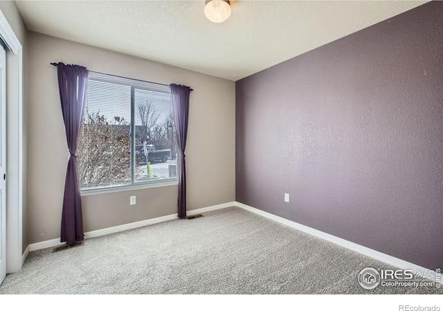 spare room featuring baseboards, carpet floors, and visible vents