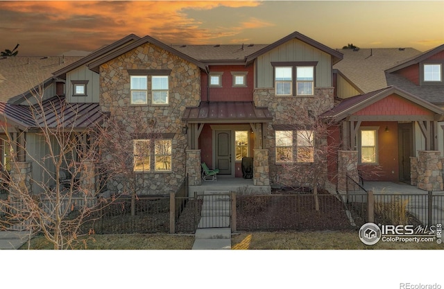 view of front of home with metal roof, a fenced front yard, board and batten siding, a gate, and a standing seam roof