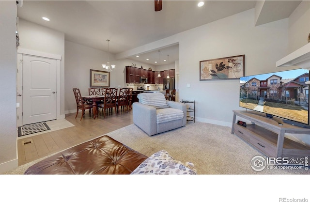 living area with light wood-style flooring, baseboards, a notable chandelier, and recessed lighting