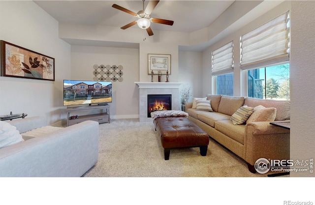 carpeted living room featuring ceiling fan, a fireplace, and baseboards