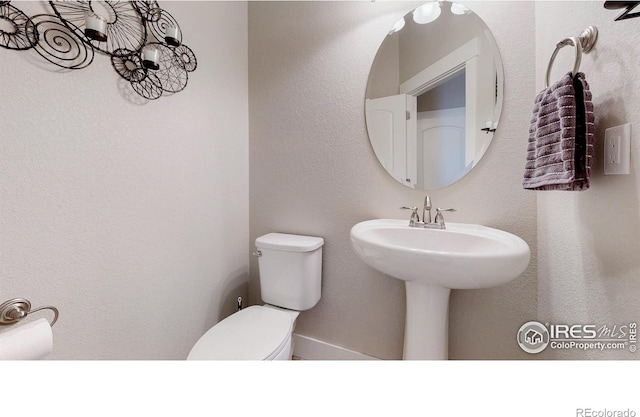 bathroom featuring a textured wall and toilet